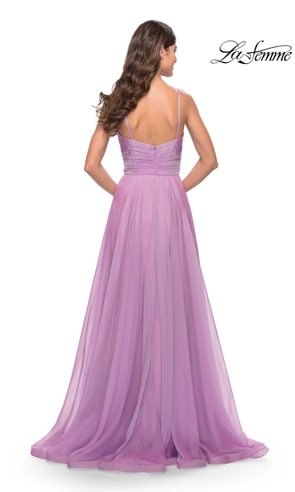 A woman with long brown hair is seen from the back, wearing the La Femme V-Neck Long A-Line Prom Dress 31500, which features a floor-length lavender chiffon design with thin straps and a ruched bodice.